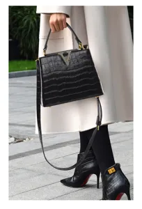 Vue détaillée du sac à main noir motif croco avec fermoir V doré, style élégant.