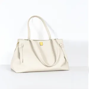 Detail view of minimalist beige leather tote bag with elegant side knot and gold metal accent.
