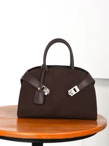 Elegante bolso de mano de ante marrón oscuro con correa envolvente chic y cierre metálico.