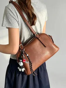 Detail view of brown soft leather shoulder bag with cute dog charm, premium casual crossbody purse.