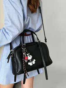 Black leather boston handbag for women, casual crossbody bag with cute dog charm accessory.