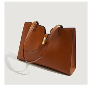 Braune Leder Tote Bag Detailansicht mit doppelten Schultergurten und goldenem Schloss.