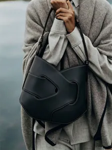 Chic minimalist black leather shoulder bag with unique sculptural cutout design for modern women.