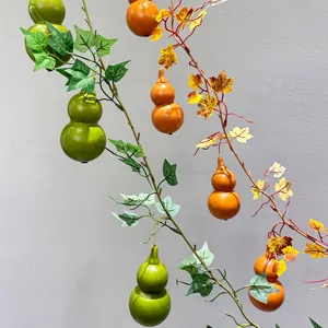 Artificial gourd vine detail showing realistic green and orange pumpkins with ivy leaves for decor.