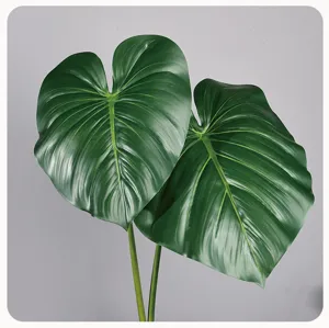 Gedetailleerde close-up van kunstmatige groene monstera bladeren met realistische textuur.