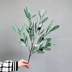 Detailopname van een kunstmatige olijftak met realistische groene bladeren en donkere vruchten.