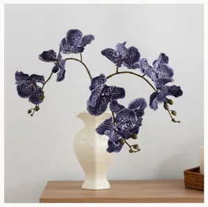 Fleurs d'orchidées violettes artificielles avec vase en céramique blanche déco maison.