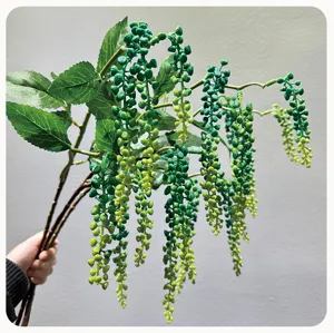 Primo piano ramo di bacche finte pendenti, foglie verdi e grappoli di frutta per decoro.