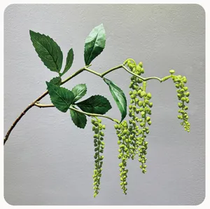 Dettaglio ramo di frutta di pianta artificiale appendiabiti, foglie verdi per decorazione.