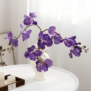 Fleurs d'orchidée violettes artificielles mouchetées en vase en céramique blanche