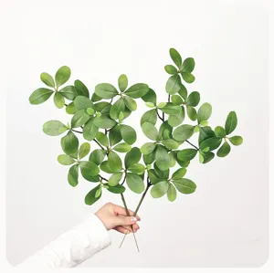 Artificial green plant branch detail, realistic bucida leaves for home decor and floral wall design.