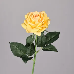 Primo piano dettagliato di fiore di rosa gialla artificiale con foglie e stelo verdi.
