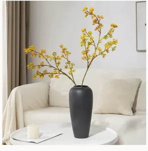 Artificial yellow fruit branch flower arrangement detail in modern vase home decor.