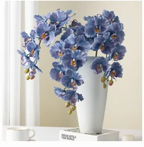 Artificial blue phalaenopsis orchids floral arrangement in elegant white ceramic vase.
