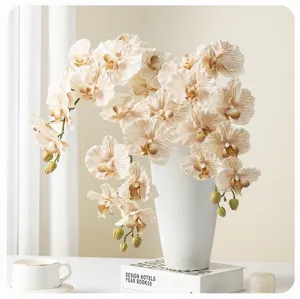 Close-up detail of artificial phalaenopsis orchids in white ceramic vase with book decor.