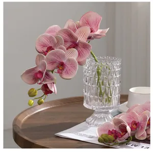 Vista dettagliata di orchidee Phalaenopsis rosa artificiali in un vaso di vetro decorativo.