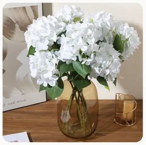 Detailed view of artificial white hydrangea bouquet in amber glass vase for home decor.