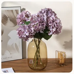 Artificial hydrangea flower bouquet in glass vase, elegant purple floral decor for home wedding party.