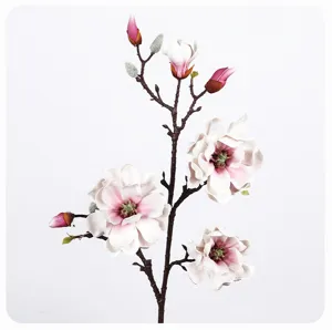Closeup detail of artificial magnolia flower branch with white petals and realistic stem.