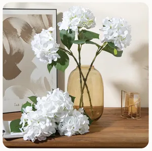 Close-up detail of white artificial hydrangea flowers arrangement in a stylish glass vase.