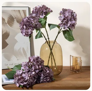 Artificial purple hydrangea flowers in glass vase, elegant home decor faux floral arrangement.