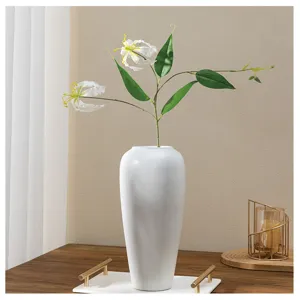 Vue détaillée rapprochée de la composition de lys artificiel dans un vase blanc élégant.