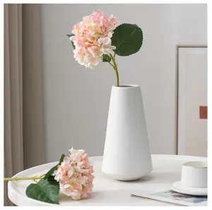 Dettaglio di bouquet di ortensie rosa artificiali e vaso in ceramica bianca minimalista