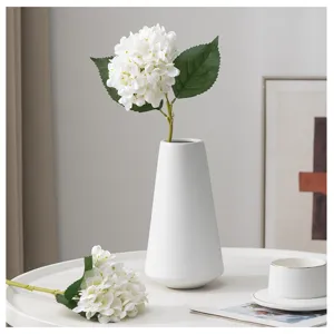 Vista dettagliata di un'ortensia artificiale bianca sistemata in un vaso di ceramica minimal.