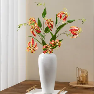 Bouquet de fleurs artificielles lys Gloriosa flamme rouge en vase blanc pour décoration.