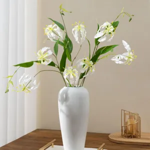 Composition florale artificielle de lys gloriosa blanc en vase blanc pour déco maison.