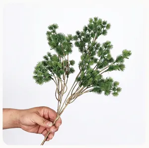 Detailed shot of artificial pine branch, realistic green pine needles with brown stem for decor.