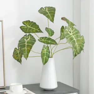 Artificial Alocasia plant leaves in white ceramic vase for home decor and indoor floral arrangement.