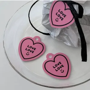 Detail van roze hartvormige cadeaulabels, love love printkaart met zwart lint op glazen schaal display