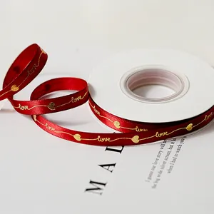 Primo piano di nastro in raso rosso con testo d'amore in folio d'oro e cuori per confezioni regalo.