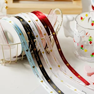 Primo piano di nastri con cuori love dorati in cesto di filo metallico per regali e dolci.