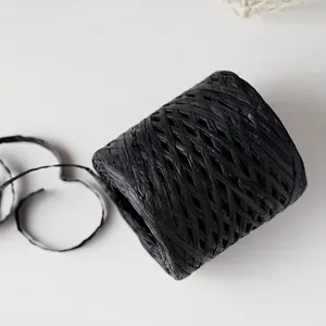 Detailed shot of black paper raffia ribbon for DIY gift box packaging and craft weaving.