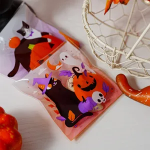 Close-up detail of Halloween cellophane cookie bags with cute black cat and pumpkin graphics.