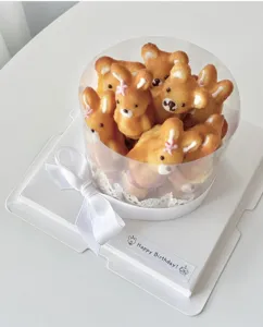 Primo piano dettagliato di dolci a forma di orsetto in una scatola regalo rotonda trasparente.