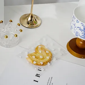 Transparent self-adhesive packaging bag with cute white heart pattern for sweet gifts.