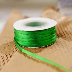 Green double-sided polyester satin ribbon close-up, perfect for gift wrapping and crafts packaging.