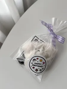 Detailed shot of the cute round birthday sealing sticker with transparent bag and purple ribbon.