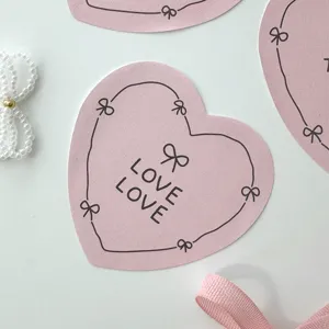 Close-up detail of cute pink heart-shaped stickers featuring hand-drawn bows and text.
