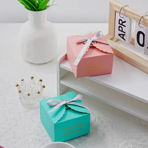 Details of the creative paper gift box with scalloped edges, silver ribbon, and gold foil text.