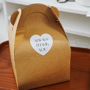 Minimalistische Kraftpapier-Geschenkbox mit süßen Bärenohren und Herz-Aufkleber für Geschenke.