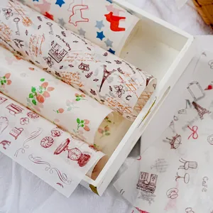 Detail view of ins-style printed parchment baking paper rolls in a white wooden tray.