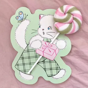 Detalle en primer plano tarjeta piruleta gato dibujos estilo ins, bonita decoración verde niños.