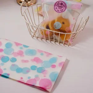 Vue détaillée de sachet d'emballage de boulangerie givré avec cercles roses et bleus et autocollant.