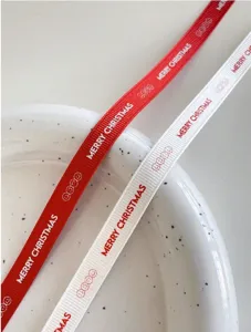 Detailed close-up view of Christmas gift wrapping ribbon with festive text and cute smileys.