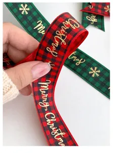Close-up detail of Christmas plaid ribbon with gold foil Merry Christmas and snowflake patterns.