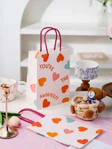 Sac cadeau en papier rose pour la Saint-Valentin avec cœurs, détail idéal pour pâtisserie.
